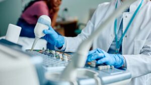 Ärztin mit blauen Handschuhen führt Ultraschalluntersuchung durch – moderne Medizintechnik im Einsatz für Diagnostik und Wissenschaftskommunikation